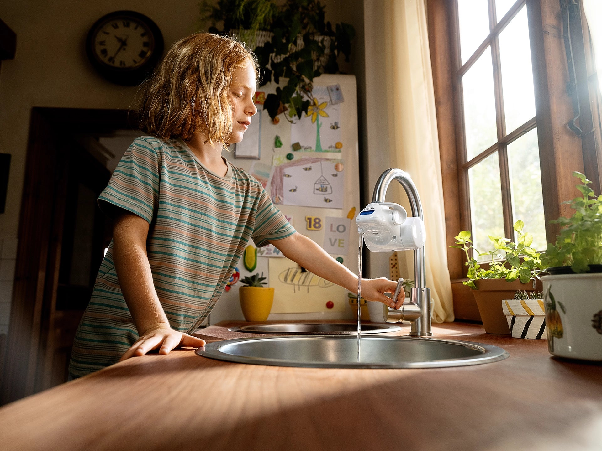BRITA ON TAP Pro water filter dispensing water into a kitchen sink.