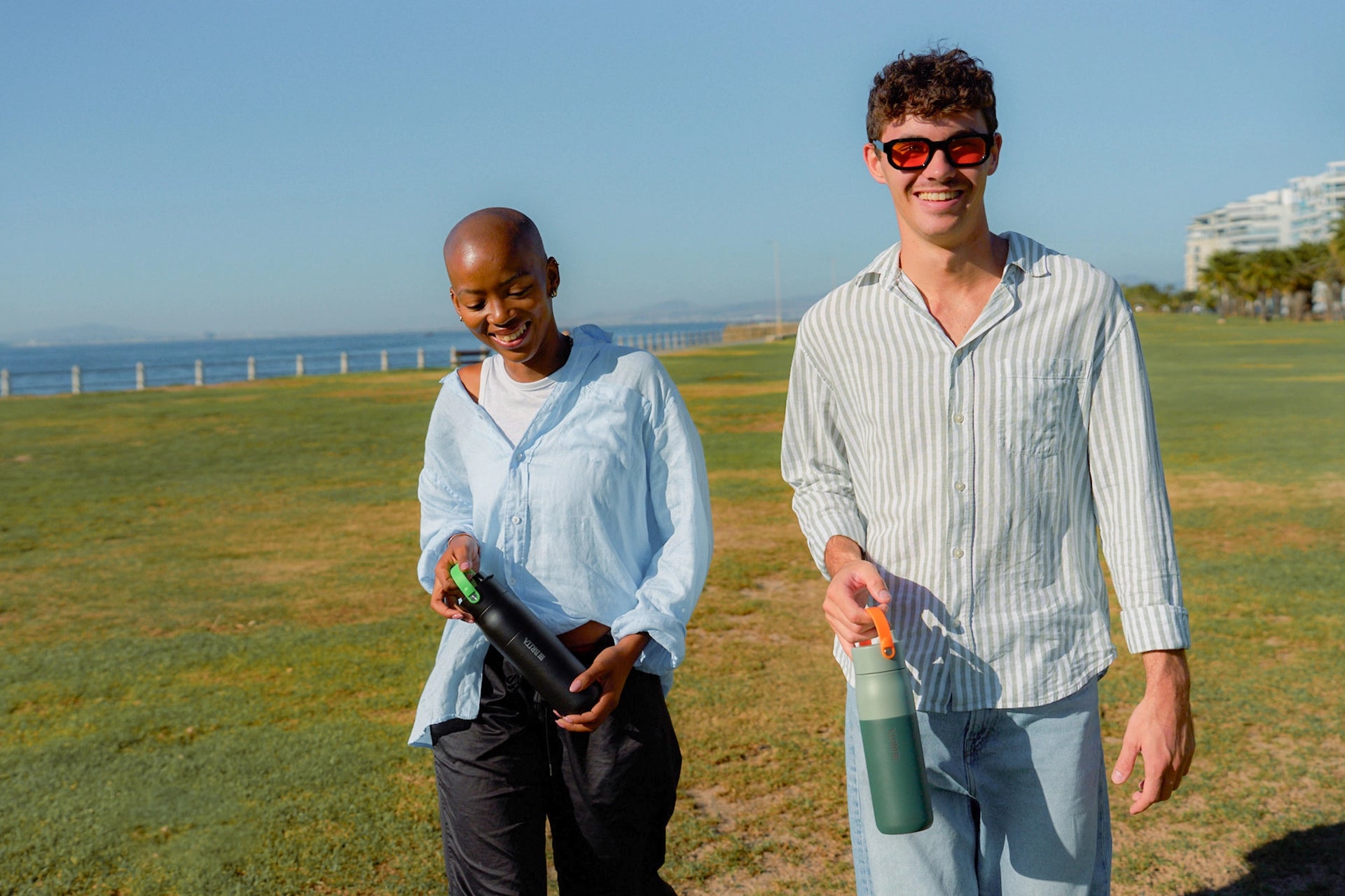 People walking outdoors carrying BRITA LARQ bottles with handle accessories