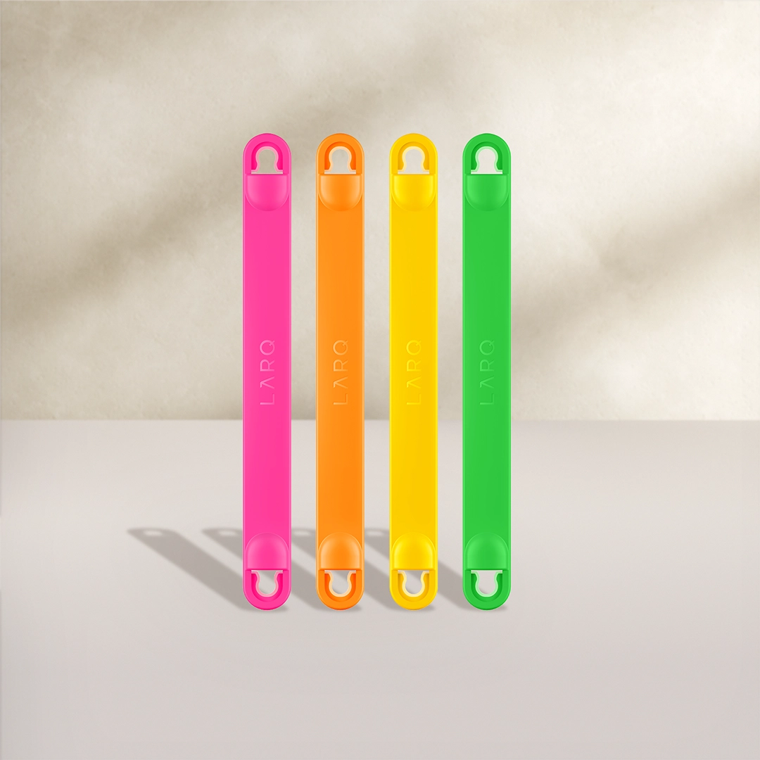 Manici per bottiglie BRITA LARQ in quattro colori: rosa, arancione, giallo e verde su sfondo beige.