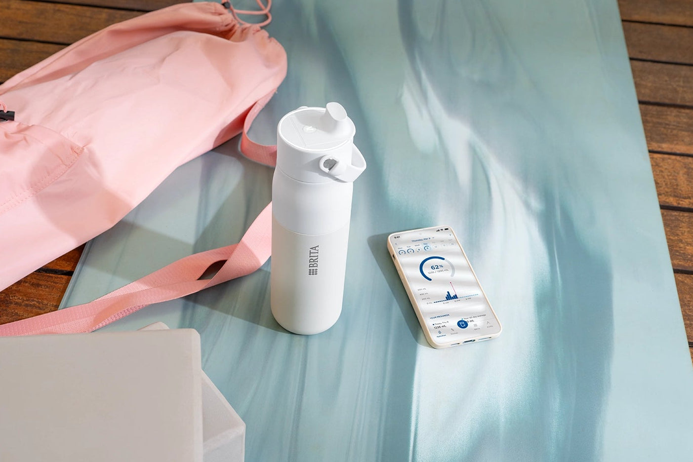 BRITA LARQ iQ Filter Bottle and smartphone with BRITA app placed on a yoga mat.