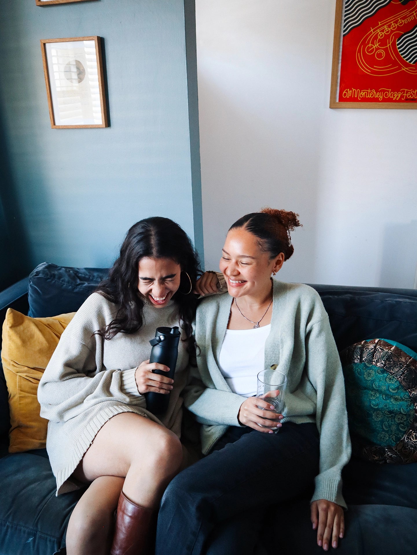 Two girls laughing and sitting on a couch with black BRITA LARQ water filter bottle.