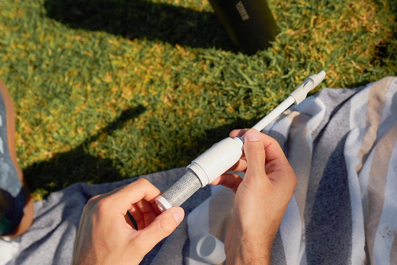 A person sitting on grass outdoors inserting BRITA LARQ filter in BRITA LARQ filter kit.
