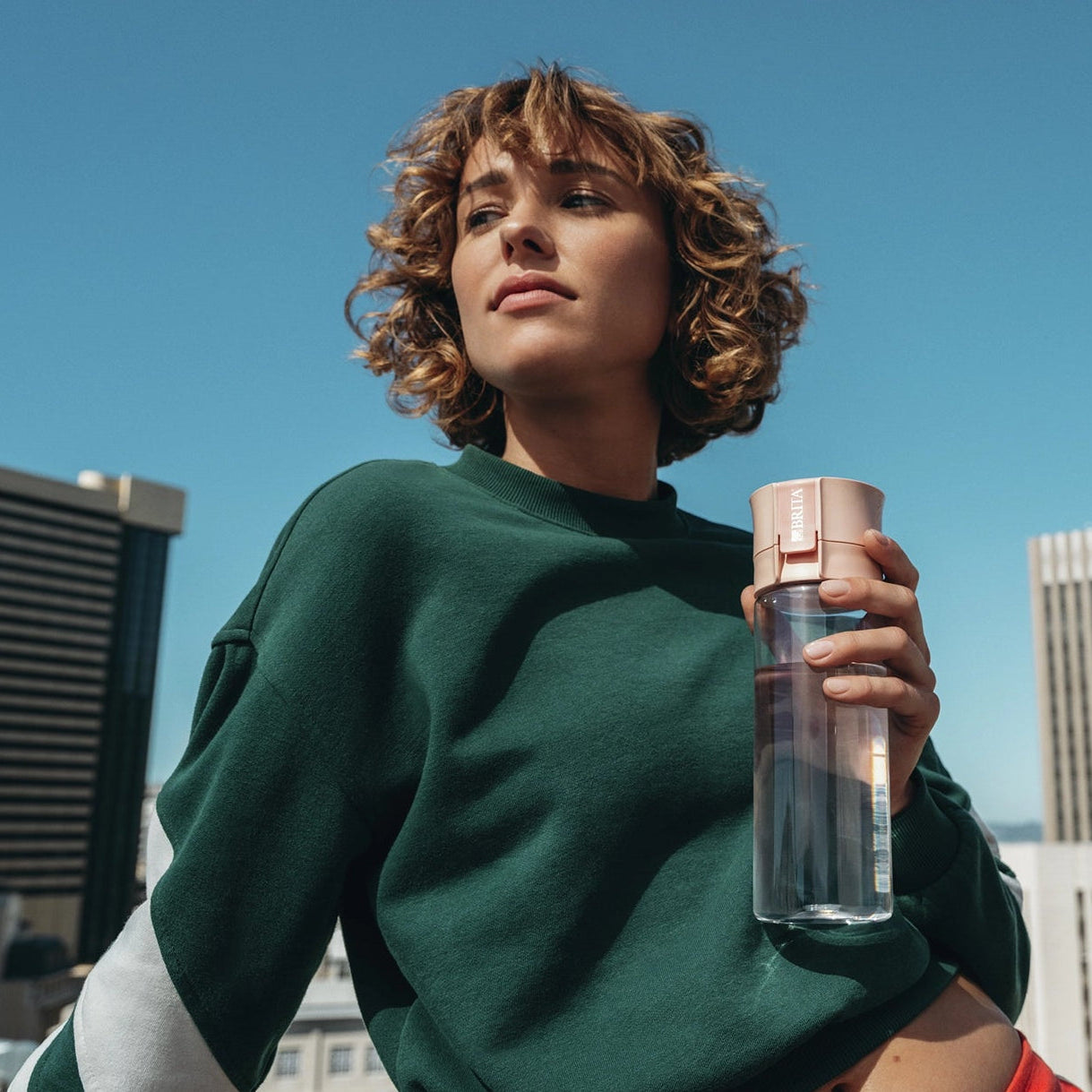Person holding a BRITA water filter bottle Model Vital with a cityscape in the background