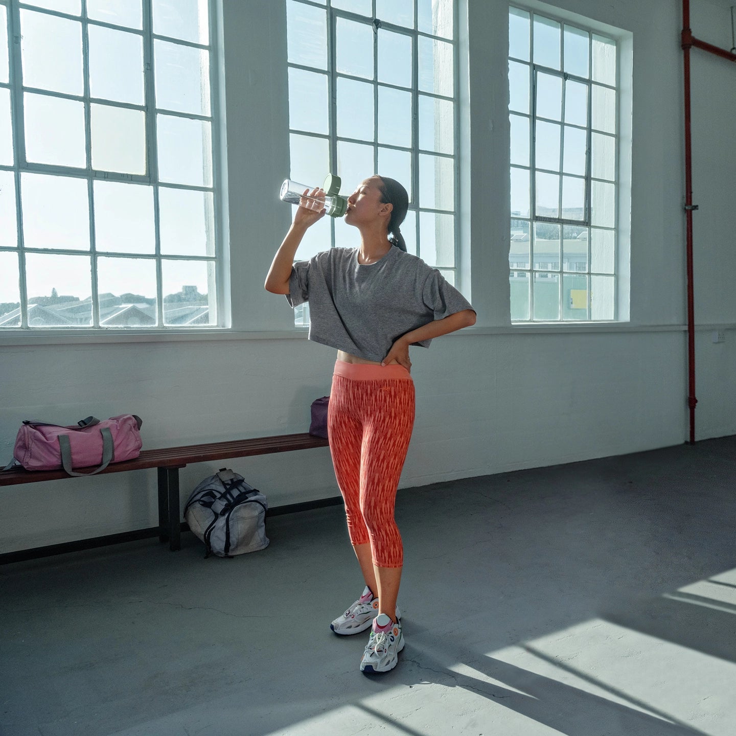 Woman drinking from green water filter bottle Model Vital in gym