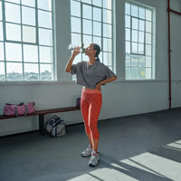 Woman drinking from green water filter bottle Model Vital in gym