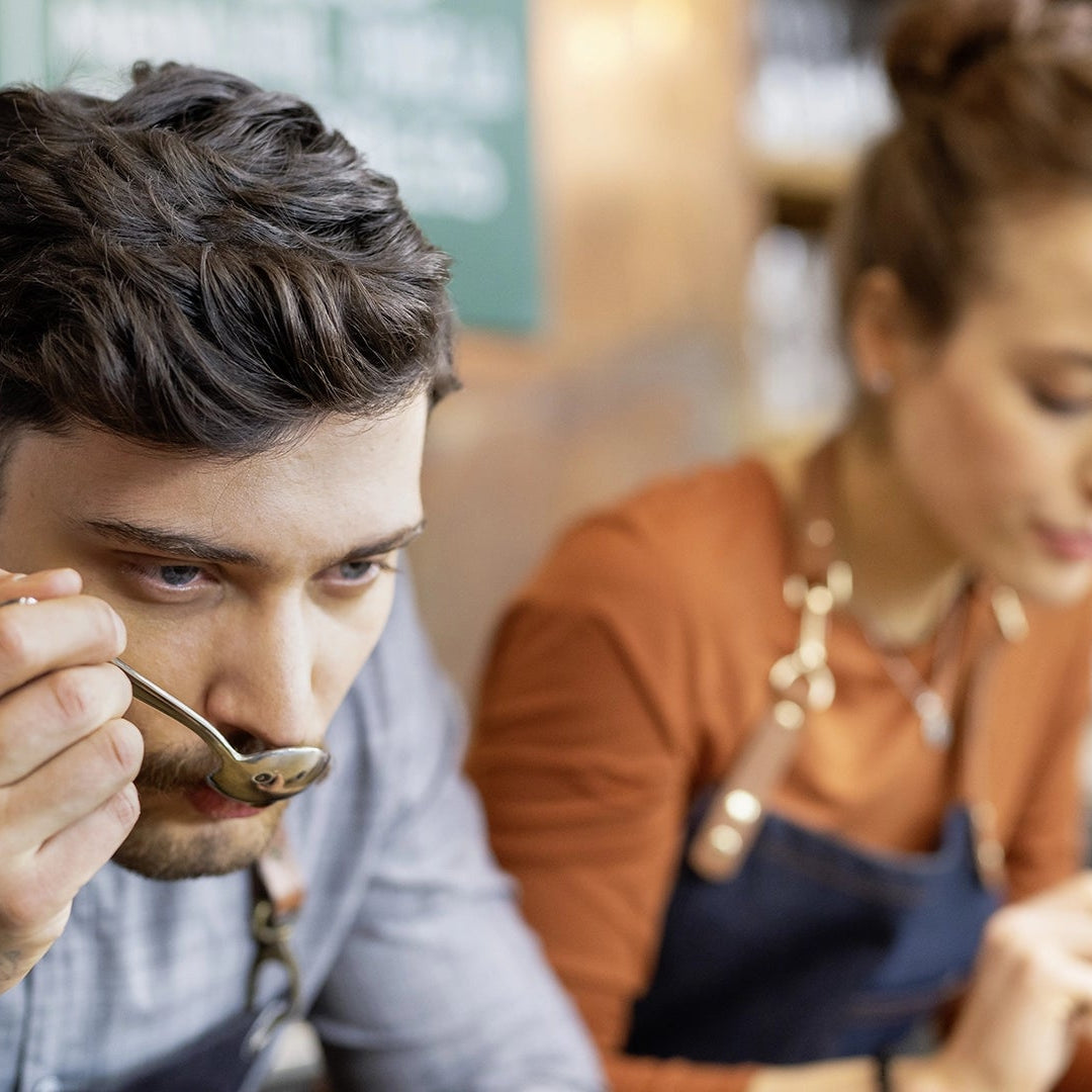 A young man and a youing woman doing a sensory test with a cup of coffee.