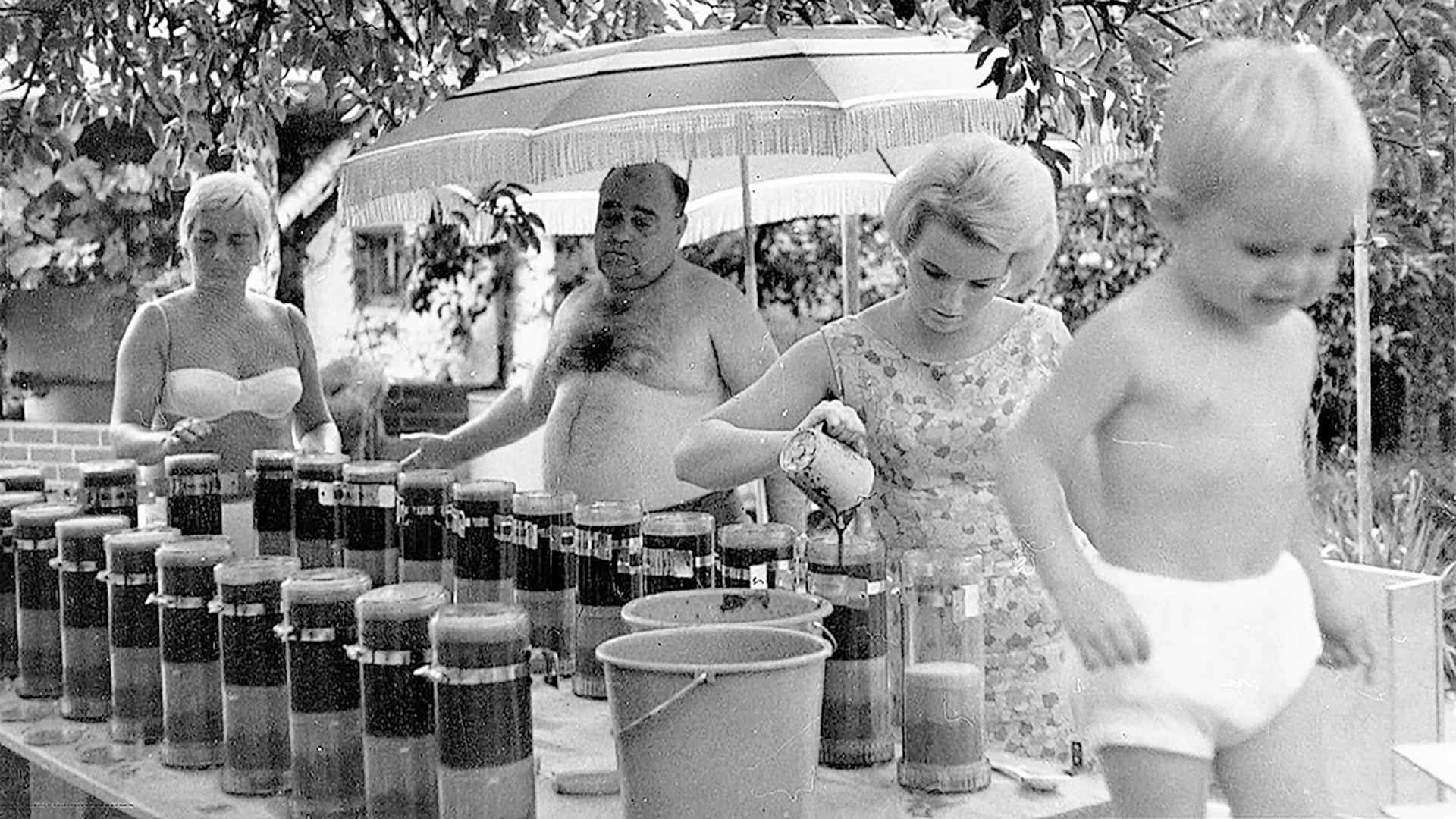 Black and white photo of Hankammer family by a table with jars and buckets outdoors.