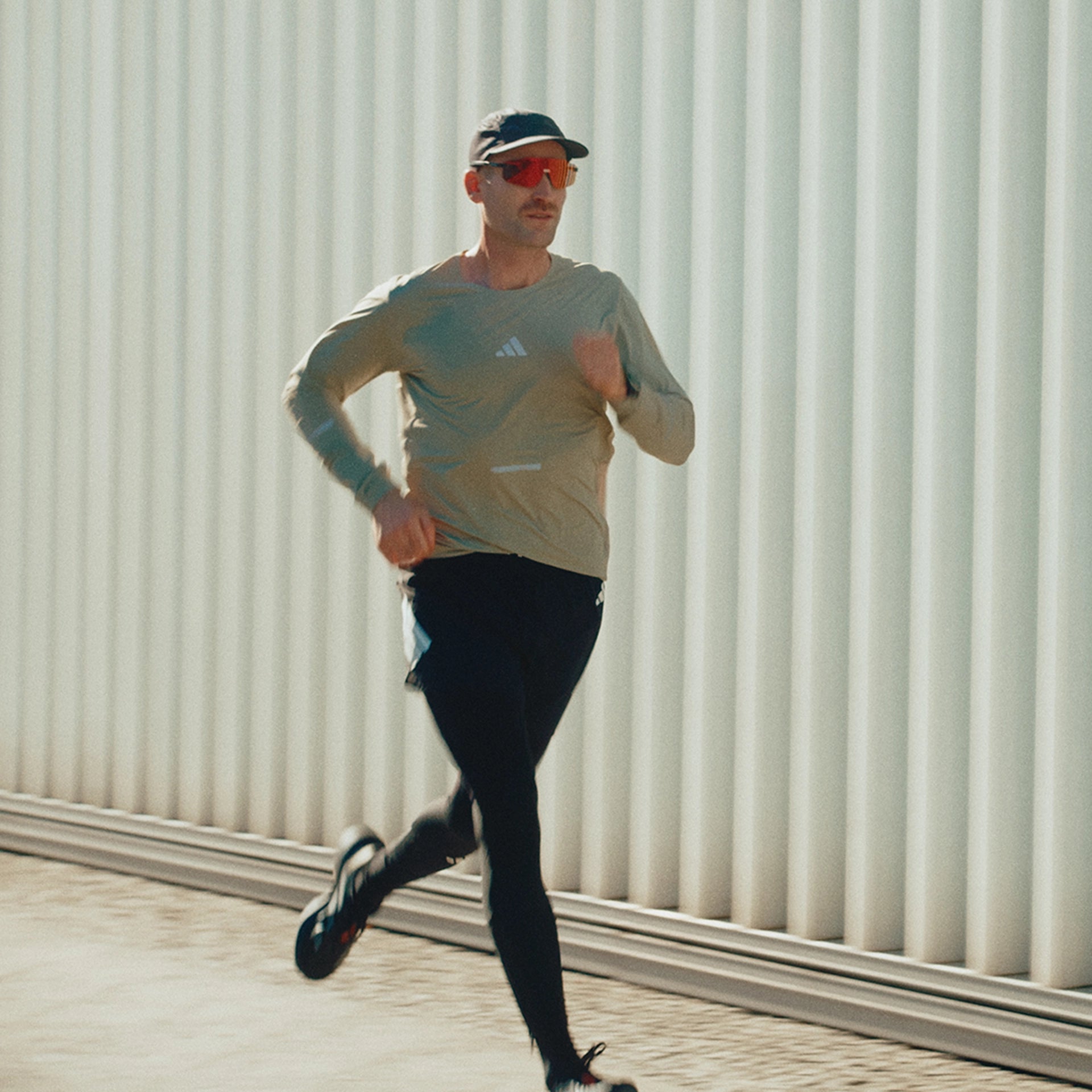 Man running outdoors with a neutral background.