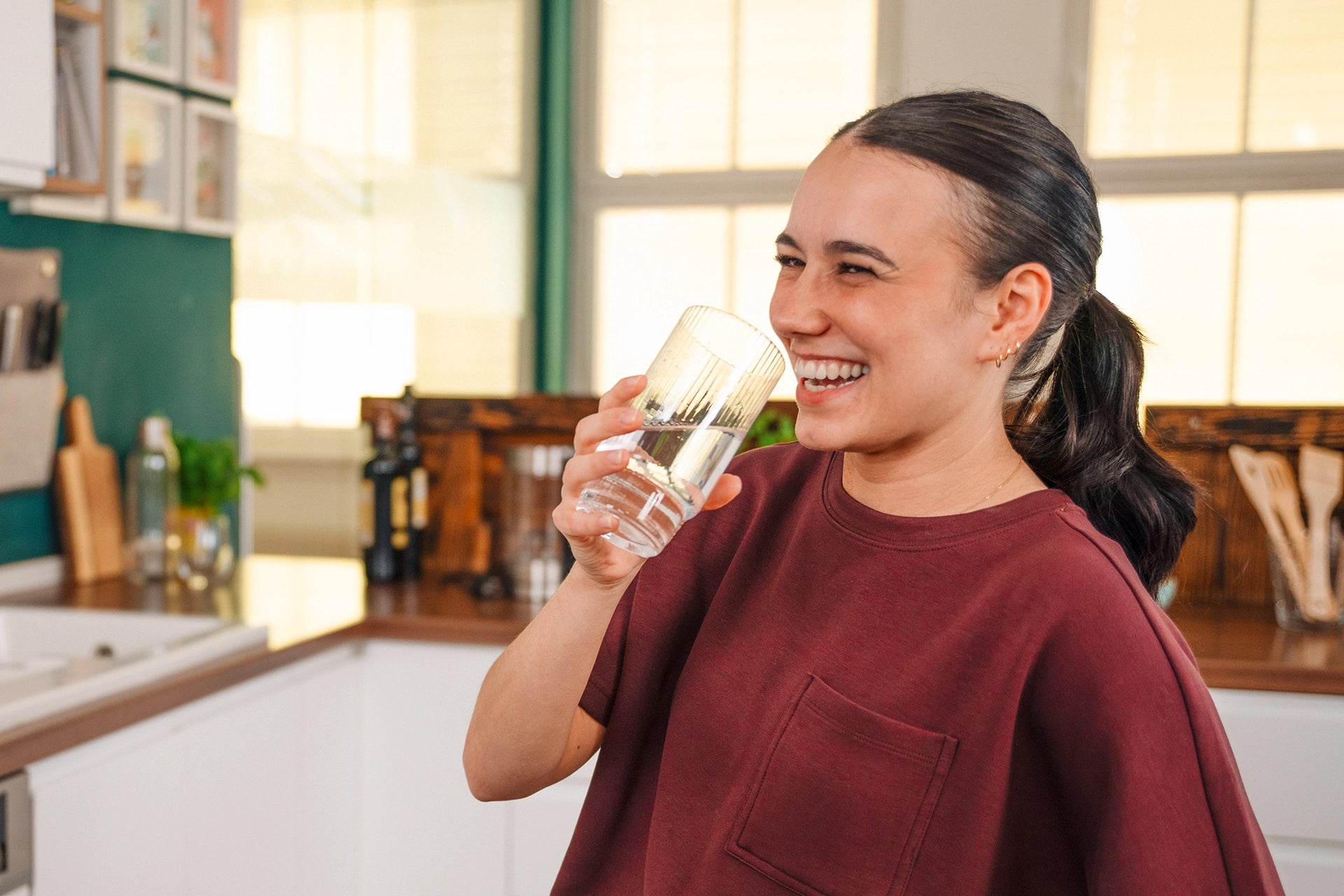 Woman holding a glass of water in a kitchen