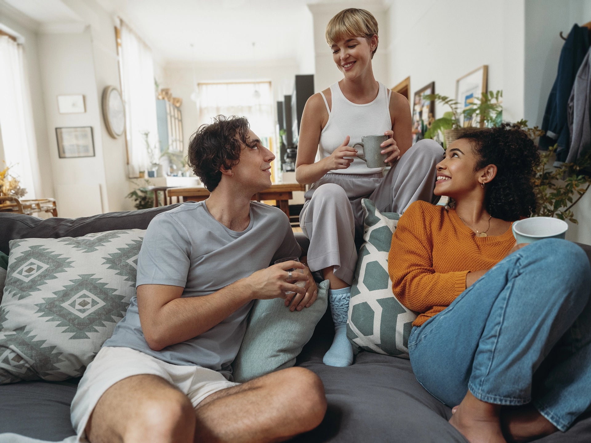 Three people sitting together on a sofa and talking indoors.