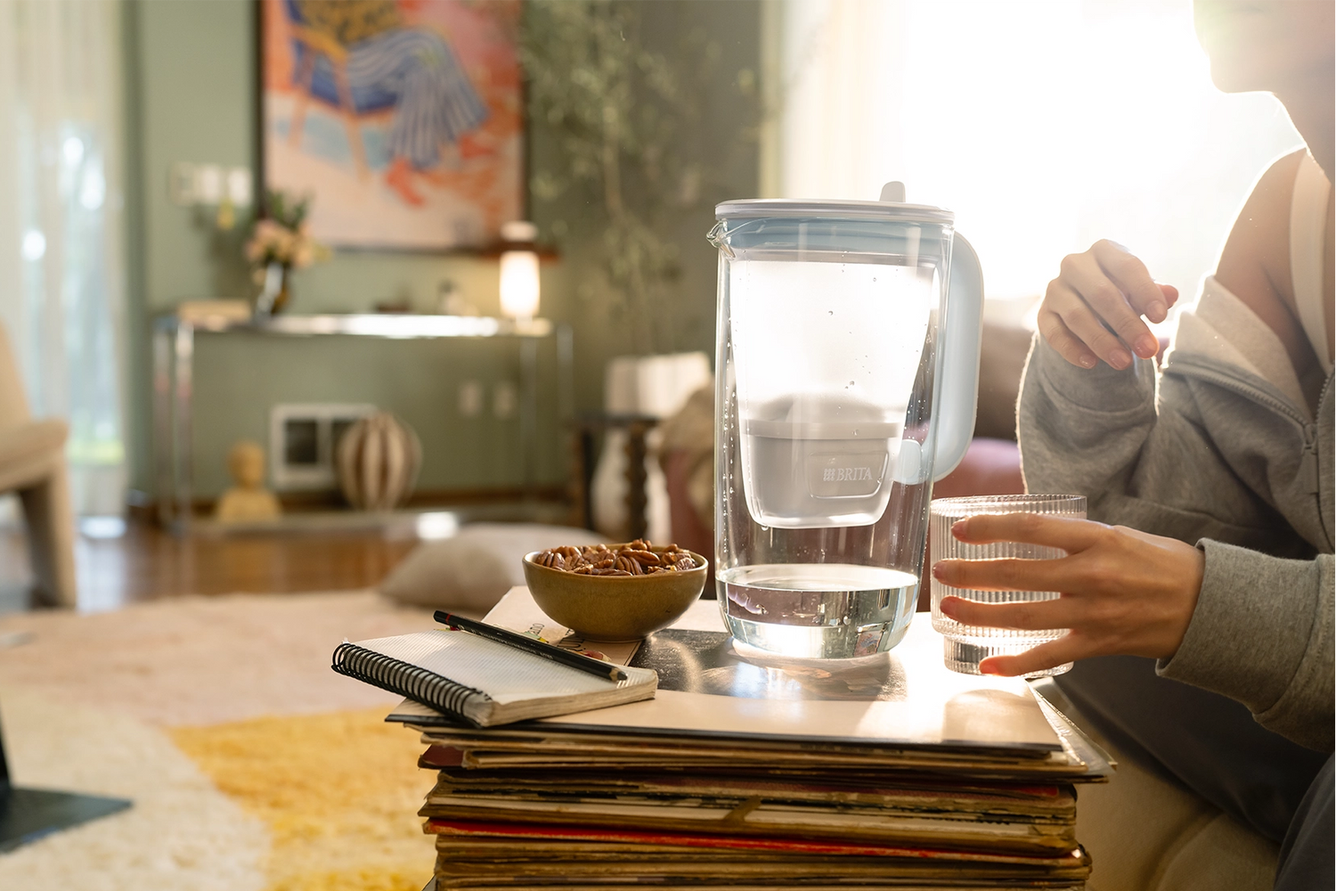 Woman sitting on a couch next to a glass jug on a table.