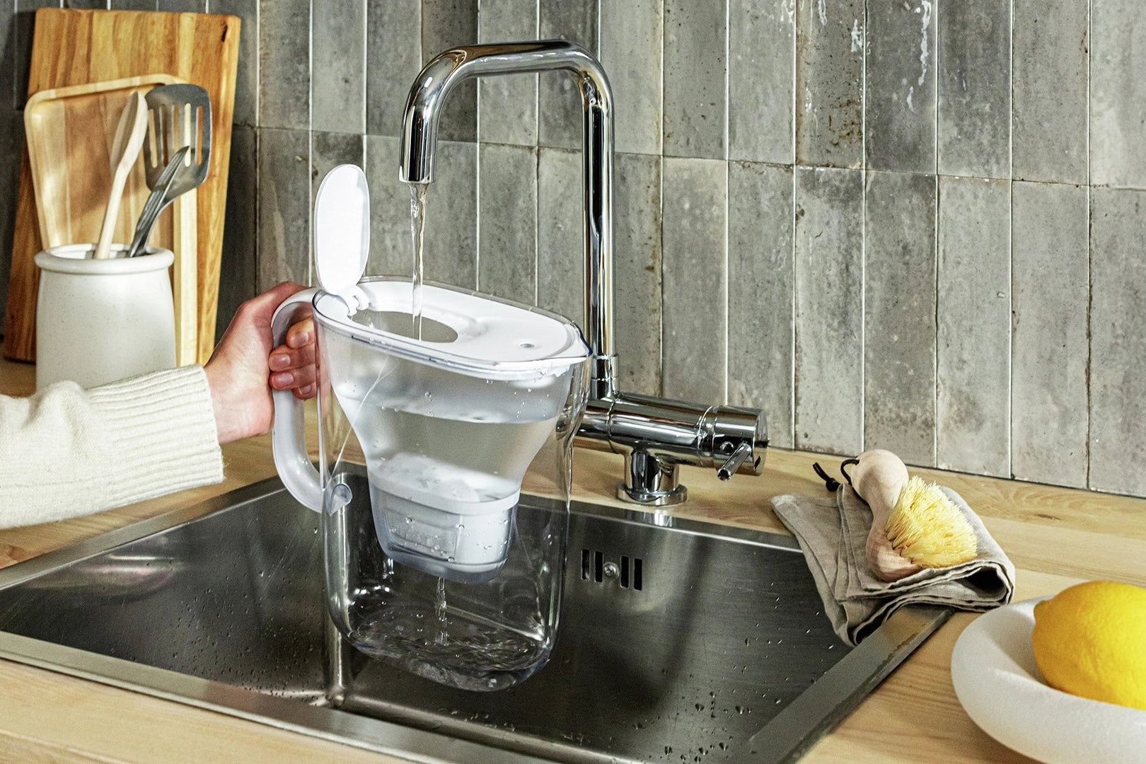 Person filling water in white water filter jug BRITA Style Essential.