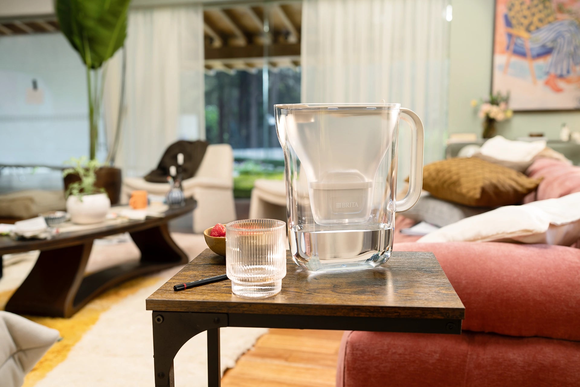 White BRITA Style Essential on a wooden side table in a living room next to a drinking glass.