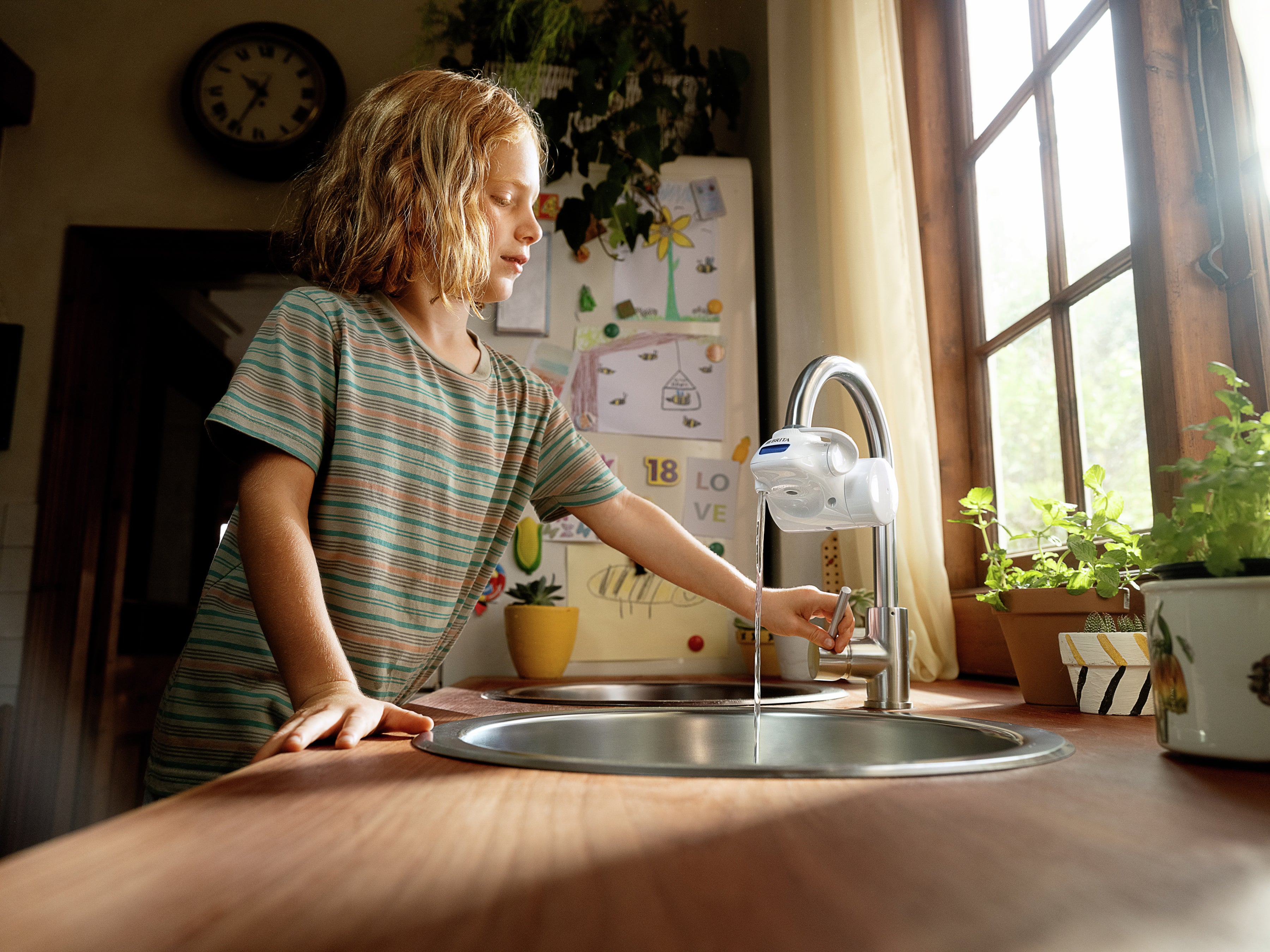 Boy using on tap pro water filter tap in kitchen
