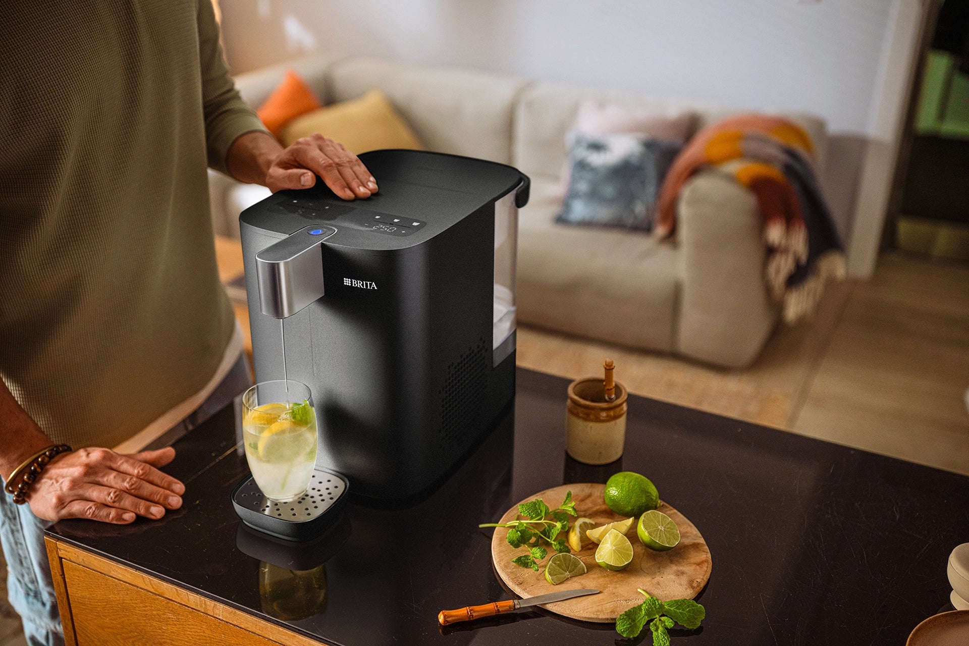 BRITA YOURCE cool dispensing water into a glass with lemon slices and mint.