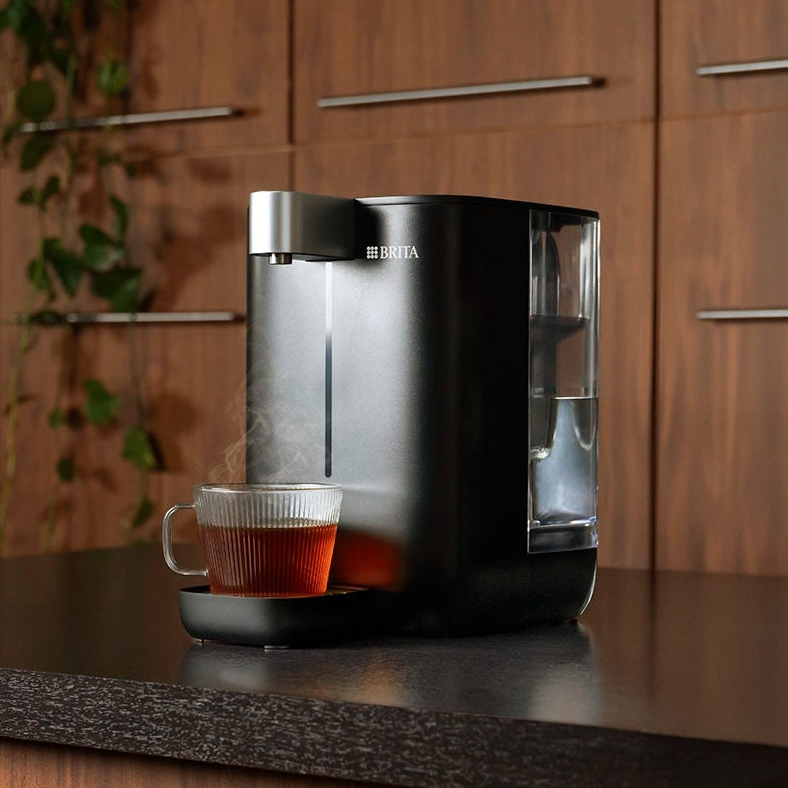 BRITA YOURCE mini water dispenser with a glass cup of freshly prepared tea.