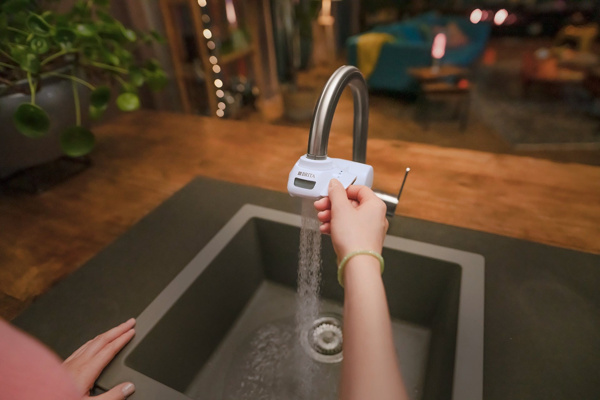 BRITA ON TAP Pro water filter dispensing water in spray mode above a kitchen sink.