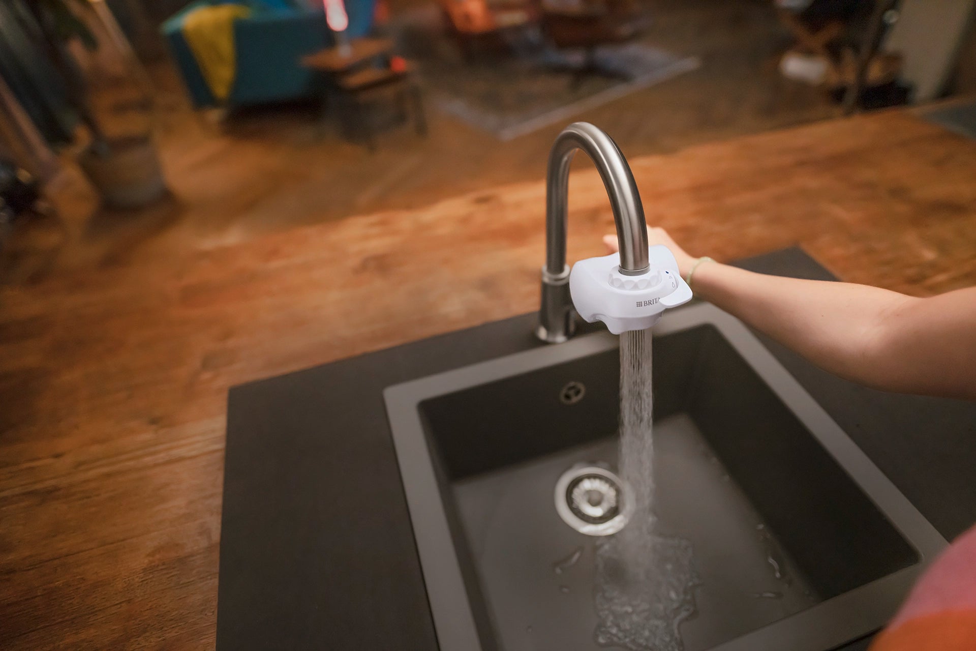 BRITA ON TAP water filter with spray mode activated above a kitchen sink.